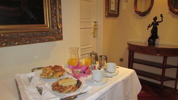 Una mesa de desayuno con cruasanes, pasteles, jugo y café.