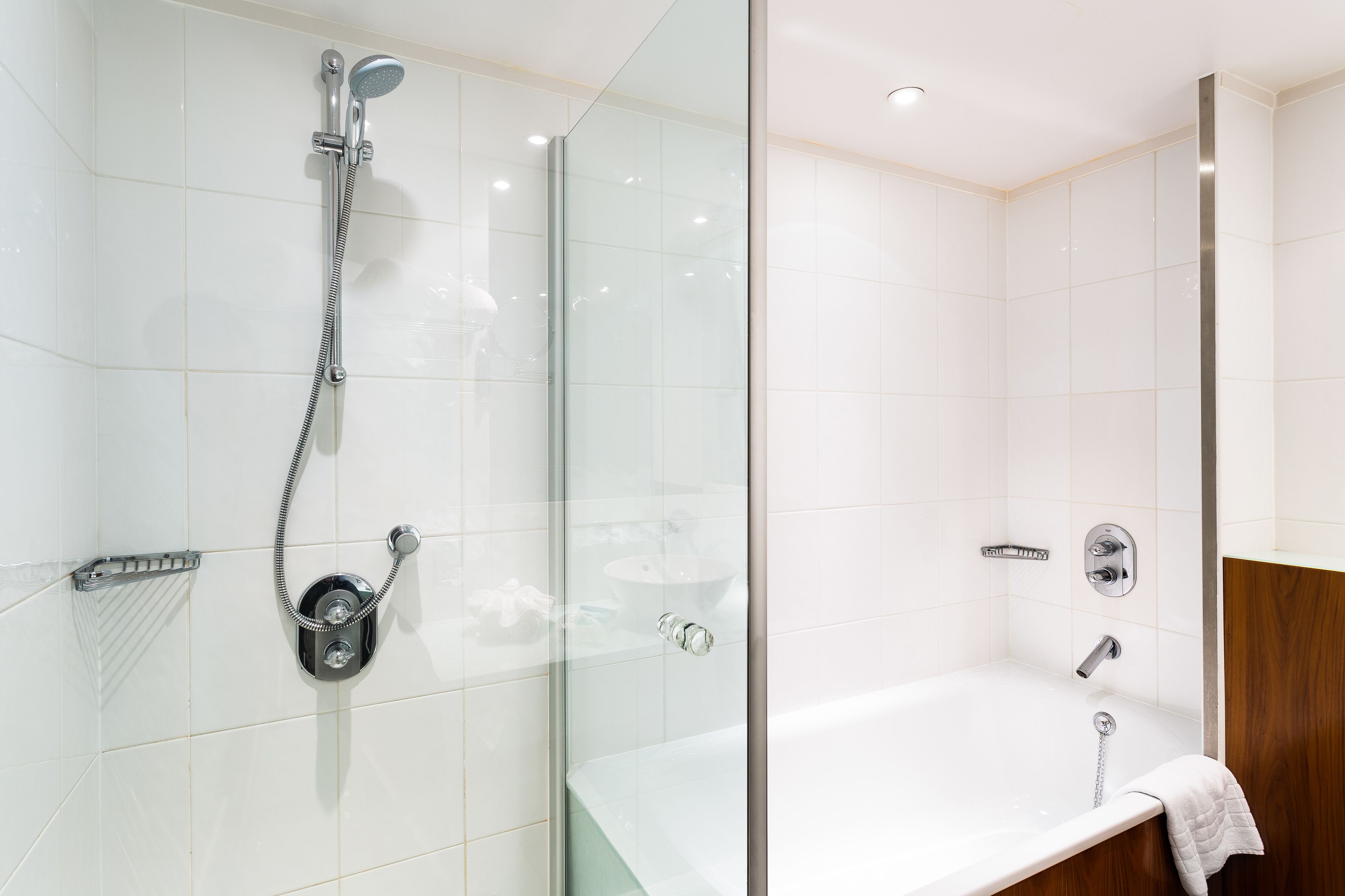 Un bagno moderno con doccia vetrata, vasca da bagno separata e mobile lavabo in legno.