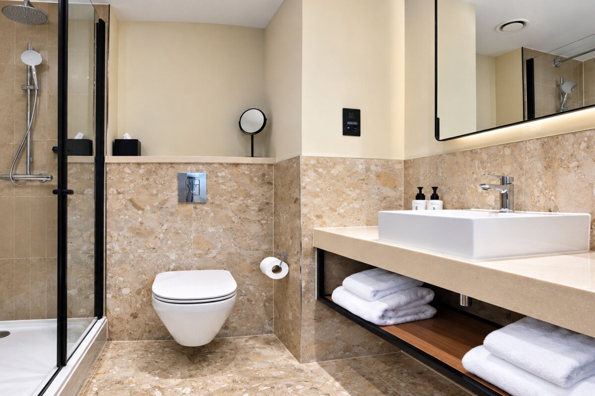 A modern bathroom with a shower, toilet, and sink.