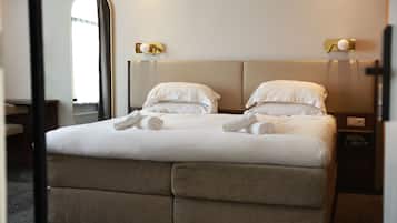 Ein Hotelzimmer mit Bett, Nachttisch, Spiegel und Wandleuchte.