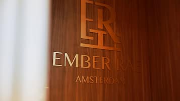 Eine Holzwand mit erhabener Beschriftung 'ER EMBER RAE AMSTERDAM'.