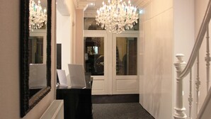A hallway with a chandelier, a mirror, and a staircase. - Sara's Boutique Hotel (Amsterdam)