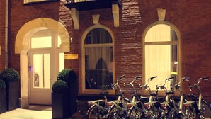 A row of bicycles parked outside a building with arched windows and a brick facade. - Sara's Boutique Hotel (Amsterdam)