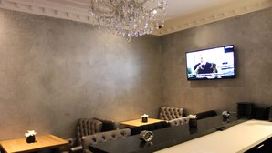 A modern bar area with a long counter, leather seating, and a television mounted on the wall. - Sara's Boutique Hotel (Amsterdam)