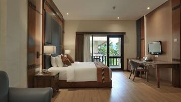 A hotel room with a bed, a desk, a chair, a television, and a balcony with a view.