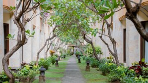 A pathway flanked by trees and stone lanterns in a courtyard. - Pelangi Bali Hotel & Spa (Seminyak)