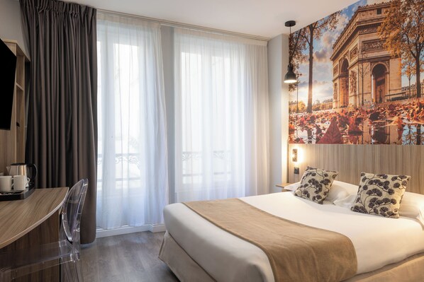 A hotel room with a bed, a desk, a chair, a coffee maker, and a large window with curtains. - Avia Saphir Montparnasse (Paris)