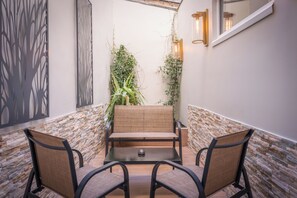 A patio area with a table and two chairs, a decorative wall, and climbing plants. - Avia Saphir Montparnasse (Paris)