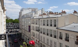 A multi-story building with white facades and shutters, featuring a pedestrian street below.