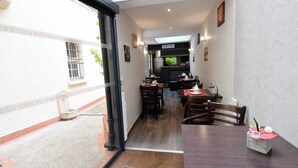 An interior view of a restaurant with a dining area, kitchen, and a small outdoor seating area. - Hôtel Saphir Grenelle (Paris)