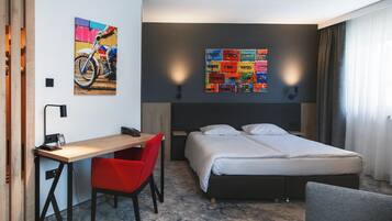 Une chambre d’hôtel moderne, équipée d’un lit, d’un bureau et d’une chaise.