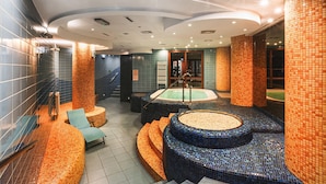 Moderni spa-alue, jossa on keskeisellä paikalla poreallas, oleskelualueita ja laatoitettu seinä.