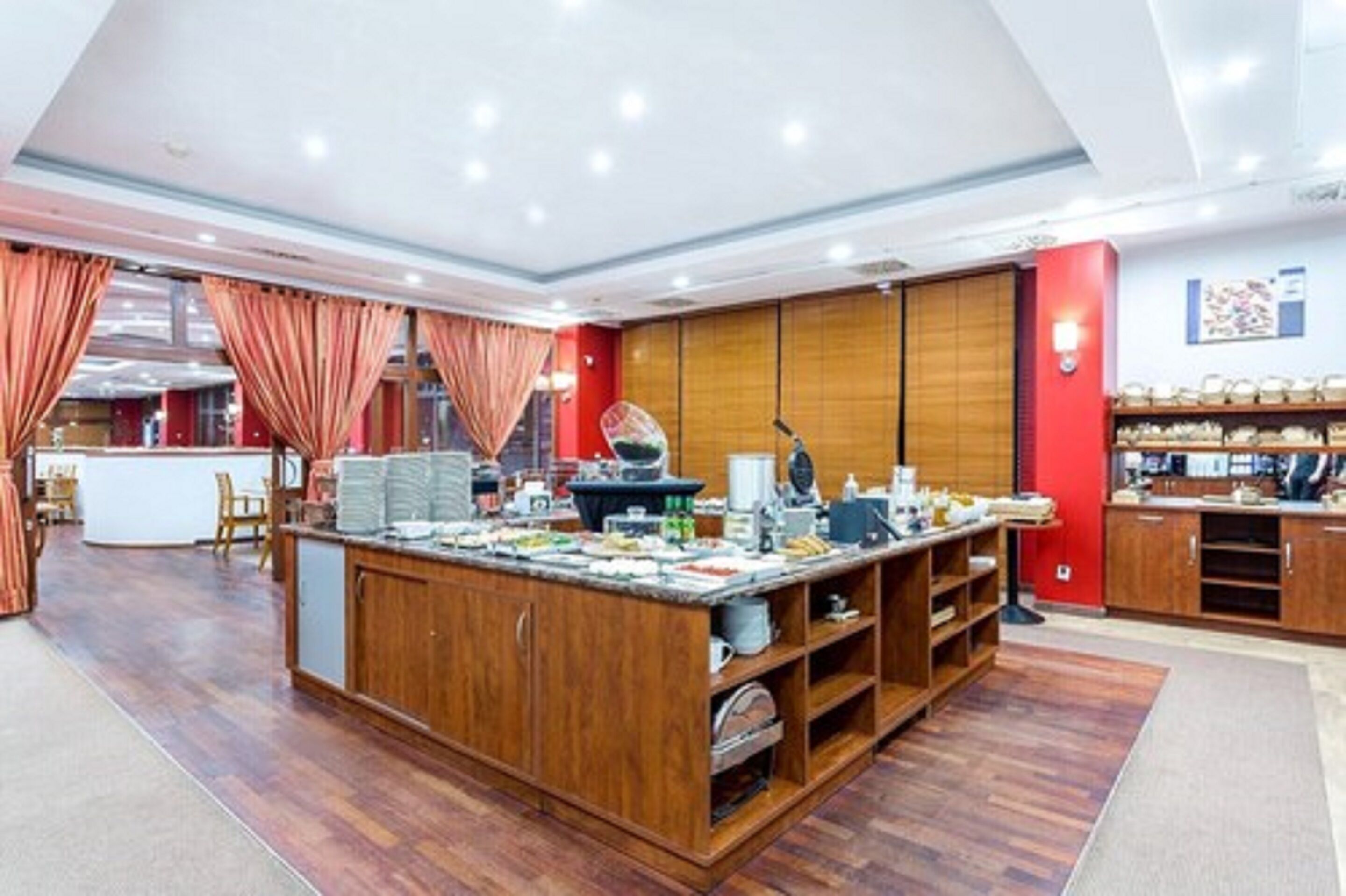 A spacious kitchen with wooden cabinets, a central island, and a red accent wall.