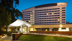 A hotel with a modern design, featuring a large parking area and a covered entrance.
