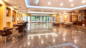 A spacious lobby with a polished floor, modern seating, and large windows offering natural light.