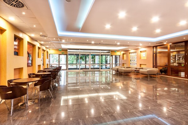 A spacious lobby with a polished floor, modern seating, and large windows offering natural light.