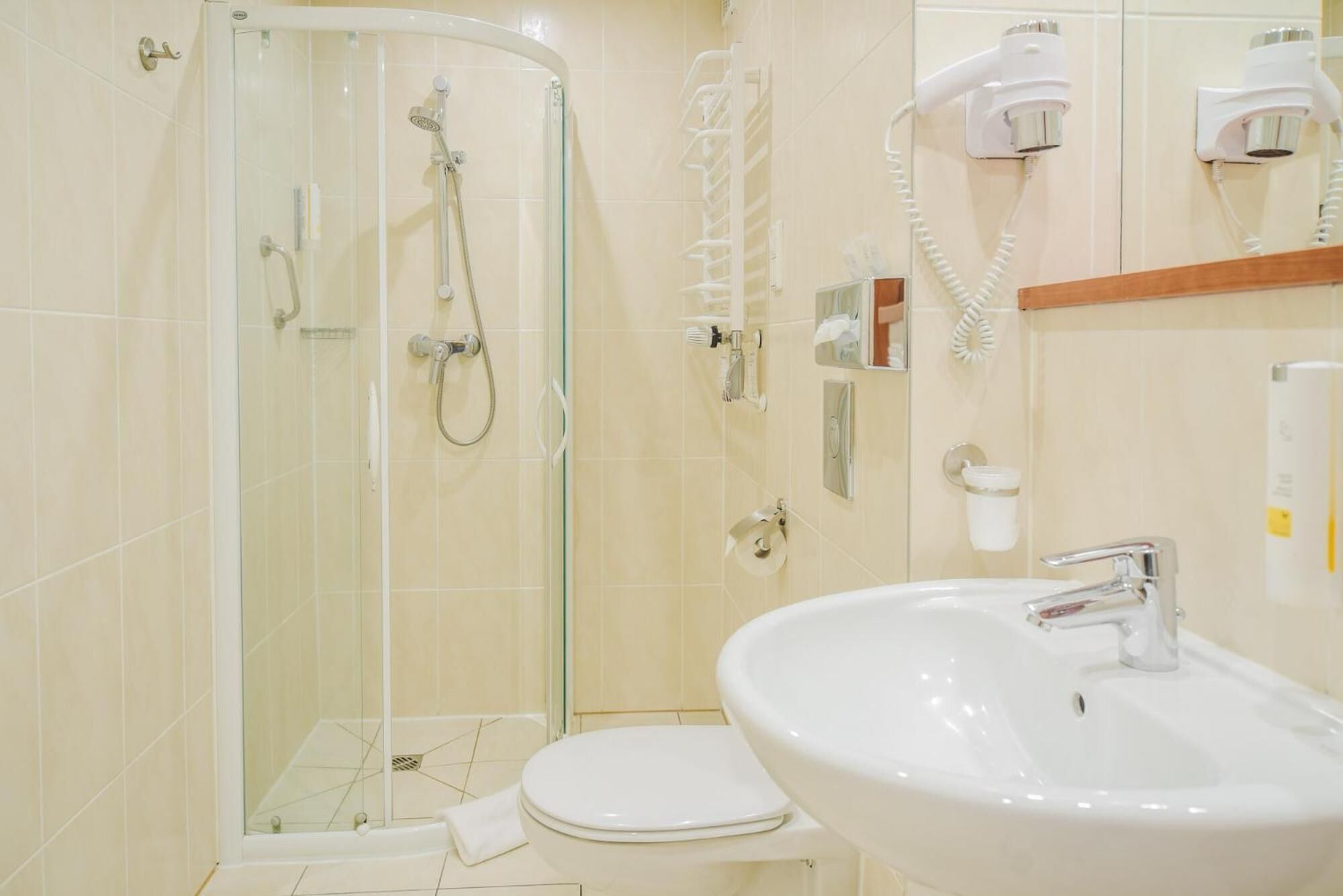 Ein Badezimmer mit einer Duschkabine, einer Toilette und einem Waschbecken mit Spiegel darüber.