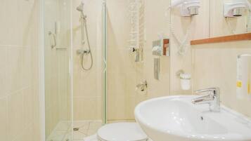 Ein Badezimmer mit einer Duschkabine, einer Toilette und einem Waschbecken mit Spiegel darüber.
