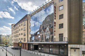 Un hotel con una amplia fachada de vidrio que refleja el cielo y un edificio en el fondo.