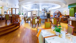A spacious restaurant with wooden flooring, multiple dining tables, and chairs.