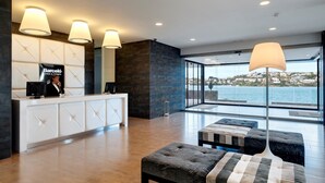 Un hall d’accueil moderne avec un grand comptoir, un réceptionniste et une vue sur la mer.