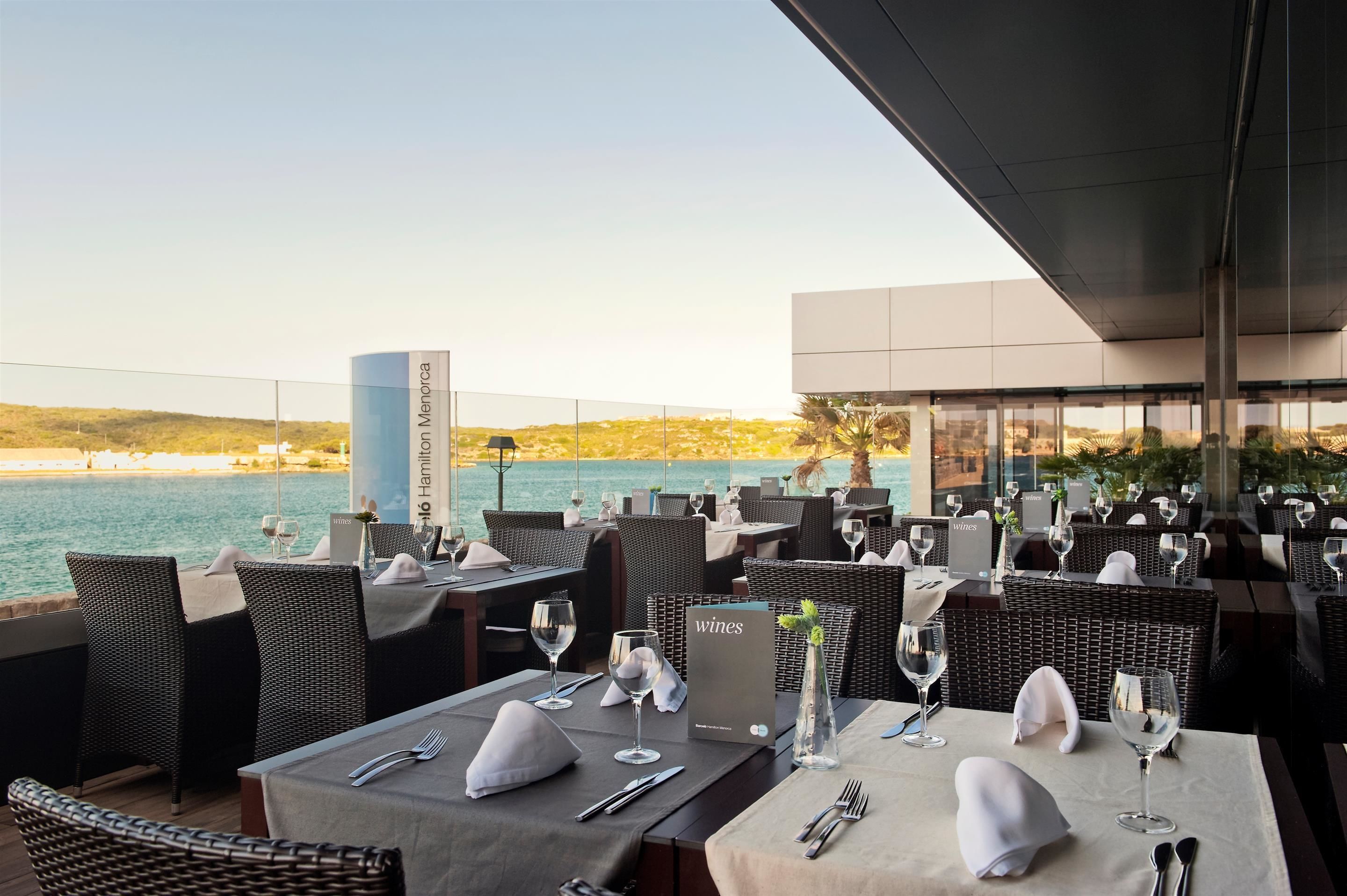 A restaurant with tables set for dining, overlooking a body of water.