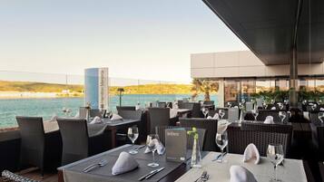 A restaurant with tables set for dining, overlooking a body of water.