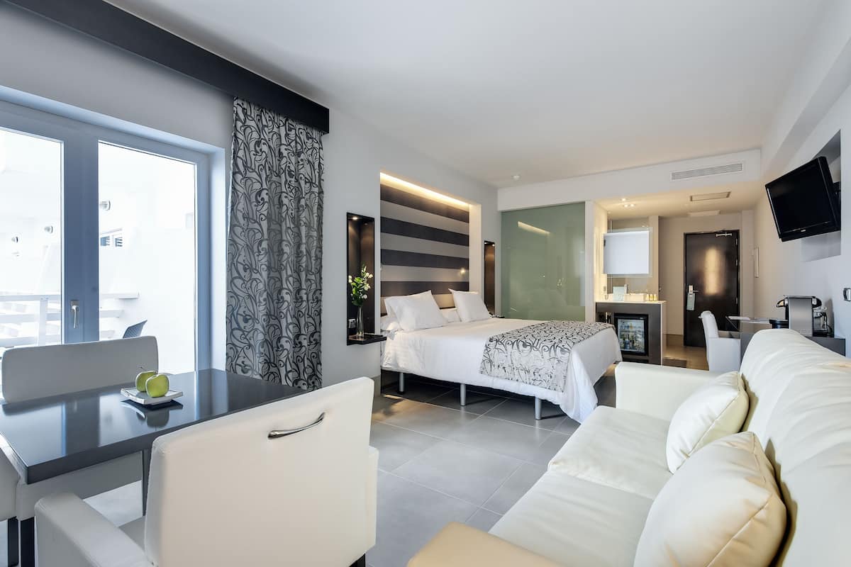 Une chambre d’hôtel moderne équipée d’un lit, d’un canapé, d’un coin repas et d’une télévision.
