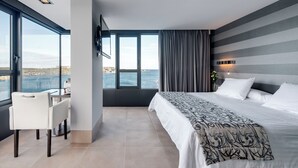 Une chambre d’hôtel moderne avec une grande fenêtre, un lit, un bureau et une chaise.