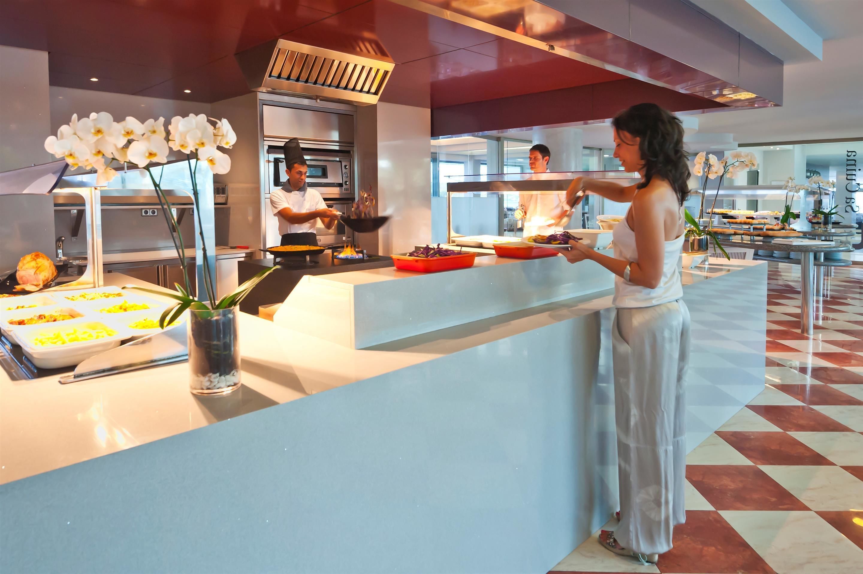 A modern hotel lobby with a check-in counter, a large oven, and a buffet area.
