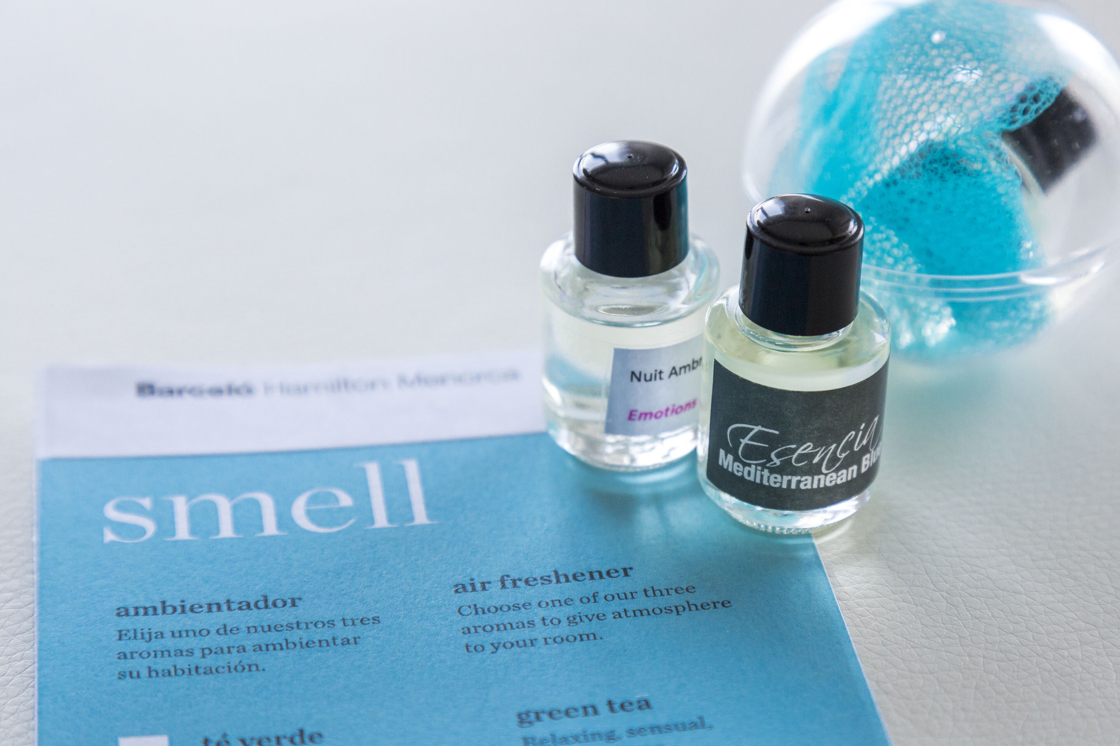 Deux vaporisateurs d’air parfumé et un petit livret bleu contenant du texte.