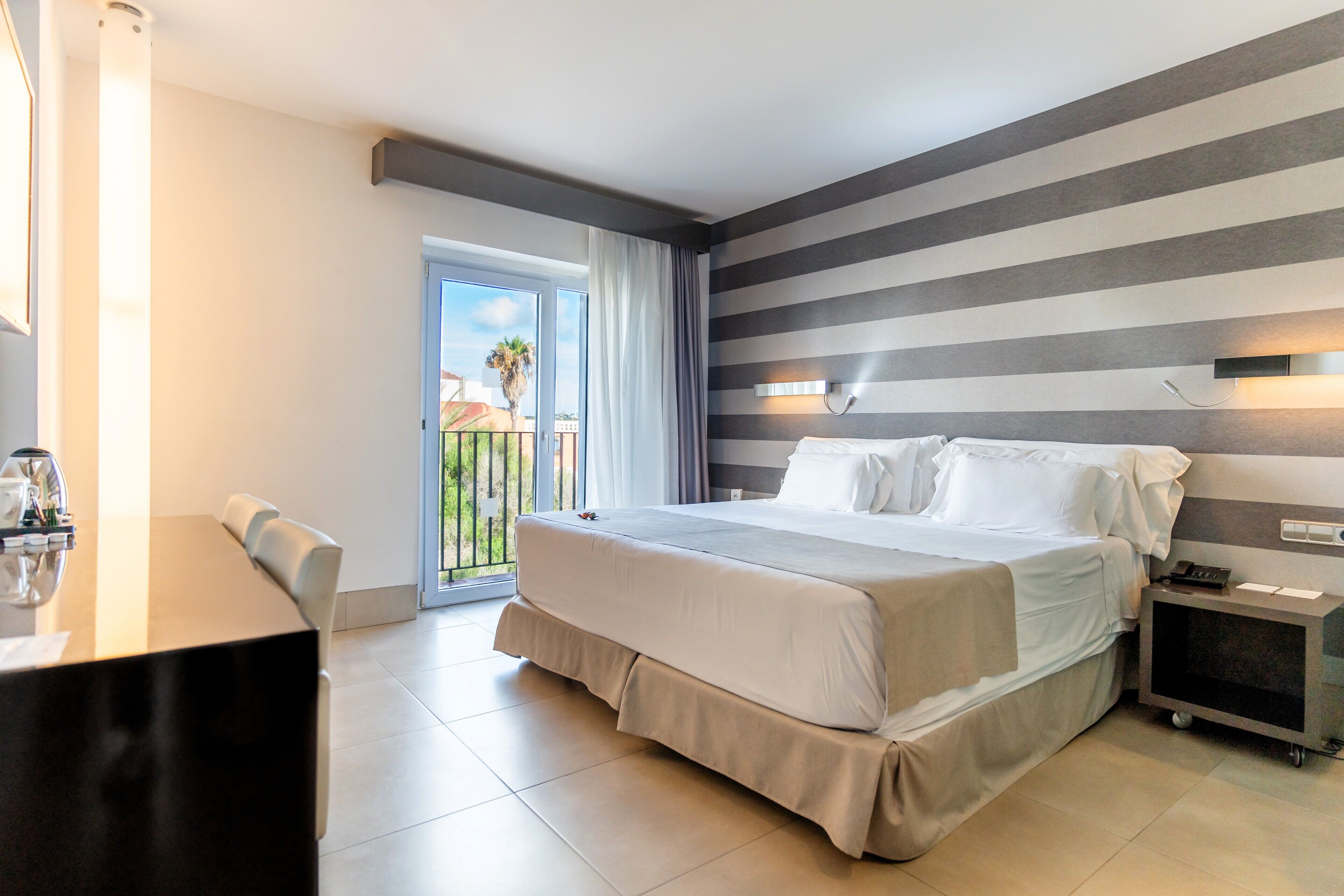 Habitación de hotel con una cama grande, un escritorio y vistas al exterior.