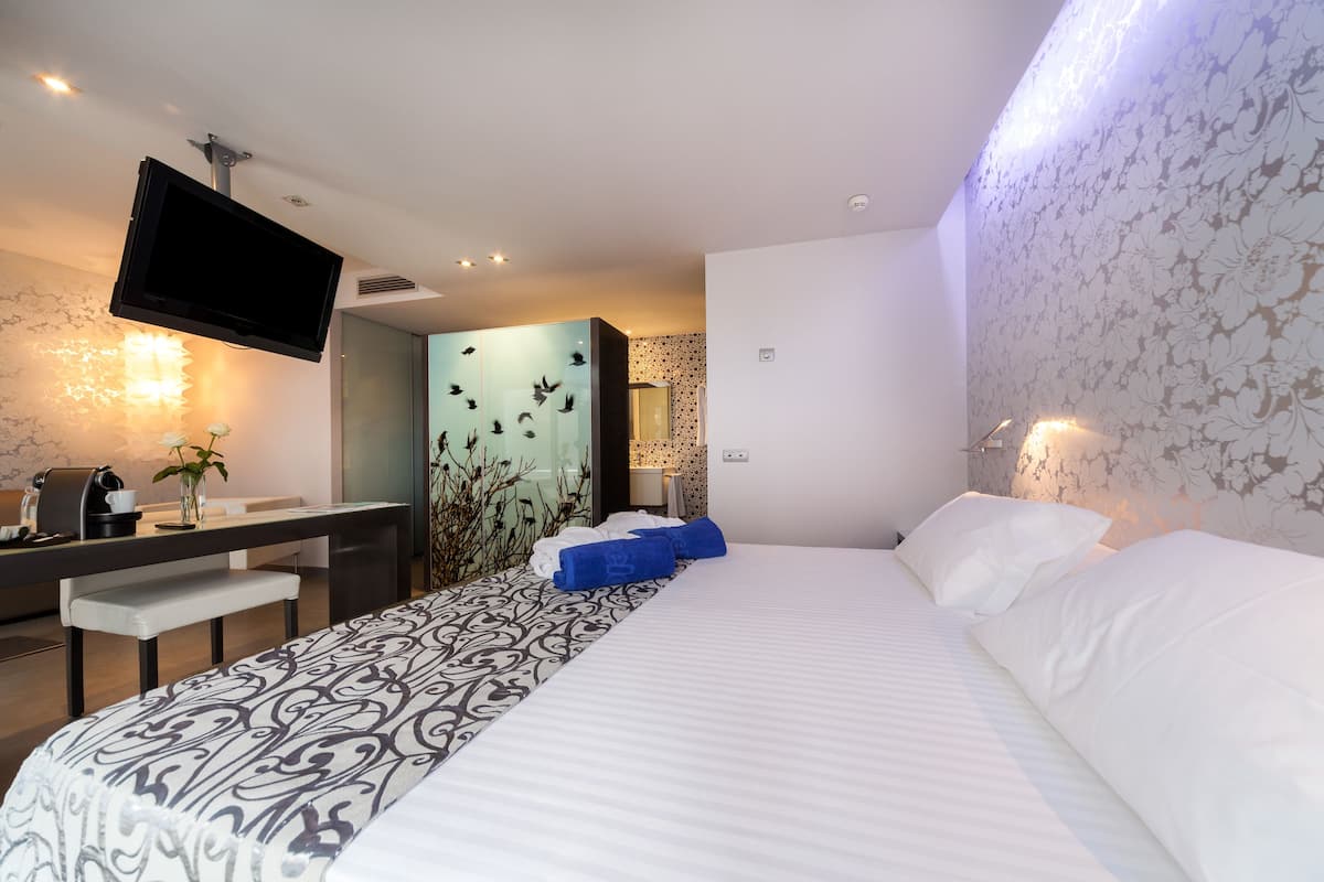 Une chambre d’hôtel équipée d’un lit, d’un bureau, d’un téléviseur à écran plat et d’une salle de bain avec une paroi en verre.