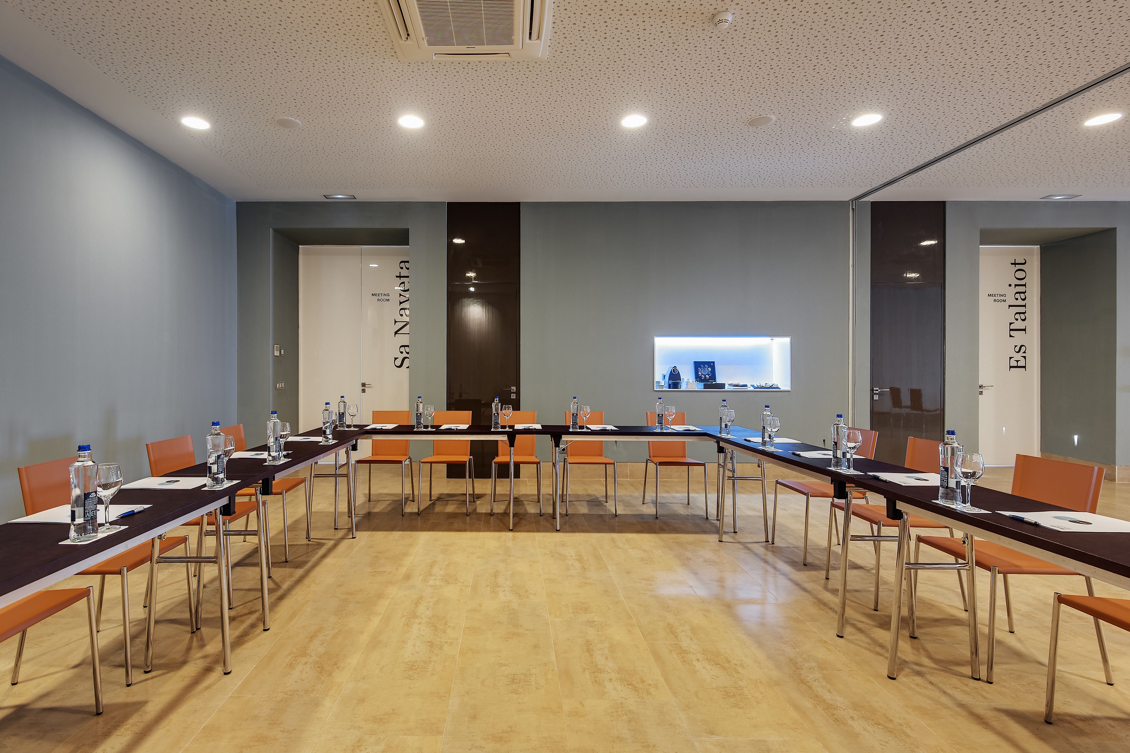 Un salón de conferencias con una larga mesa, sillas y una pantalla para proyector.