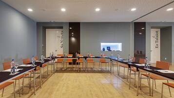 Un salón de conferencias con una larga mesa, sillas y una pantalla para proyector.