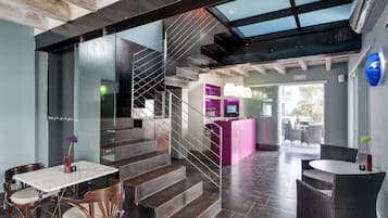 Un interior moderno con una escalera, una zona de comedor con una mesa de mármol y un mostrador de recepción.