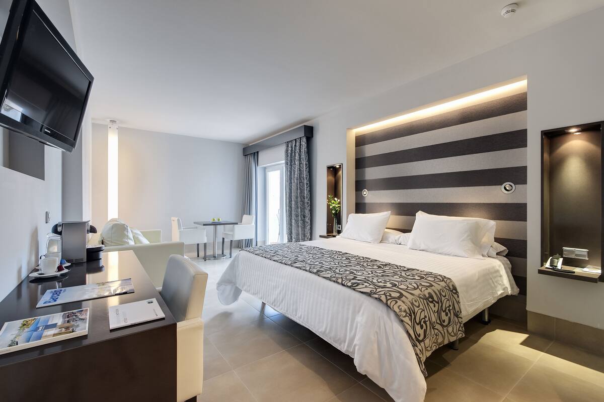 Une chambre d’hôtel moderne dotée d’un grand lit, d’un bureau avec une chaise, d’une télévision à écran plat et d’une table de chevet.