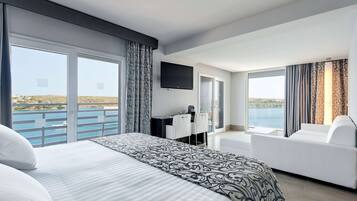 A hotel room with a large bed, a desk, a TV, and a sofa.