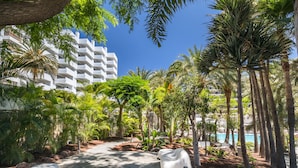 Un resort con piscina, palmeras y un camino que lleva a un edificio con balcones.