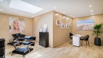 A modern salon with a skylight, several hairdressing chairs, a reception desk, and a large beach-themed painting.