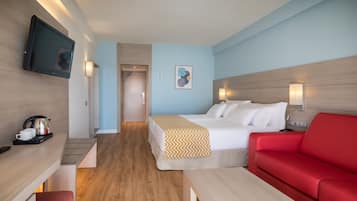 Ein modernes Hotelzimmer mit einem Bett, einem roten Sofa, einem an der Wand befestigten Fernseher und einer Kaffeemaschine auf dem Nachttisch.