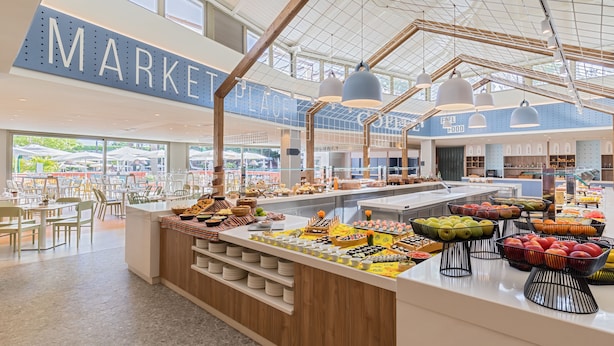 Zona de bufé con una variedad de alimentos y un letrero grande que dice 'MARKET PLACE'.