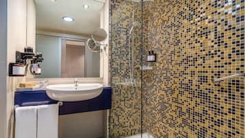 Un baño moderno con lavamanos, espejo y ducha.