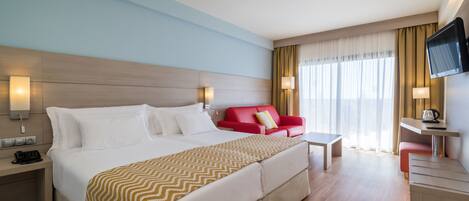 Una habitación de hotel con una cama grande, un sofá rojo, un escritorio y un televisor.