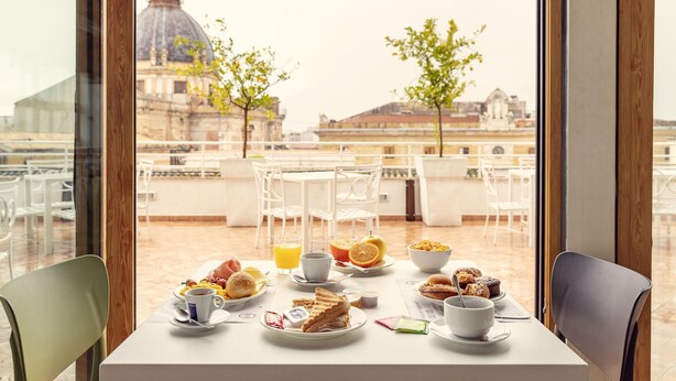 Una mesa de comedor con alimentos para el desayuno y vistas a un edificio histórico.
