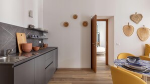 Una cocina moderna con armarios grises, una encimera de madera y un fregadero. Hay platos decorativos en la pared y una zona de comedor con sillas amarillas y una mesa.
