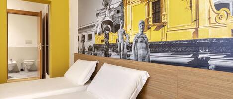 A hotel room with a bed, a nightstand, and a wall mural.