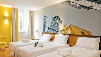 Camera d'albergo con due letti, una parete gialla e un grande murale raffigurante un edificio.