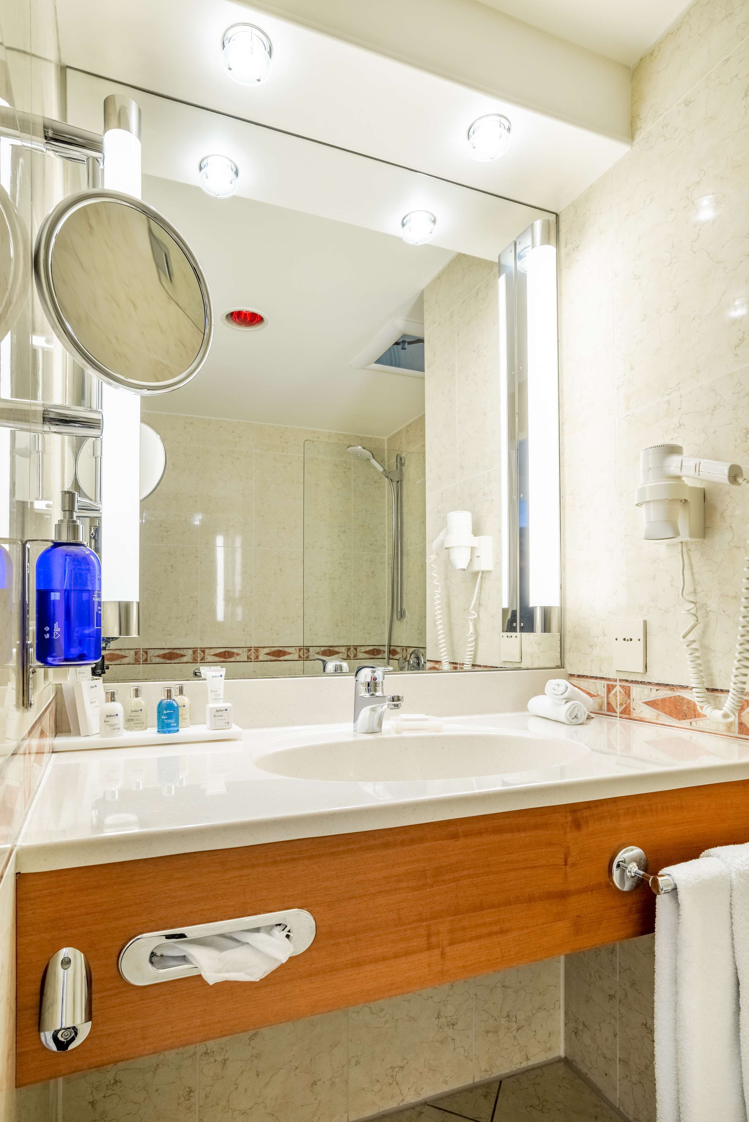 Un baño moderno con lavamanos doble, un espejo grande, un secador de pelo y un perchero para toallas.