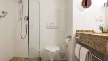 A modern bathroom with a glass-enclosed shower, a toilet, and a granite countertop with a towel hanging on the side.